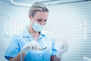 Female dentist in surgical mask holding dental tools