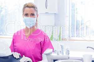 Portrait of a dentist in mask looking at camera beside chair