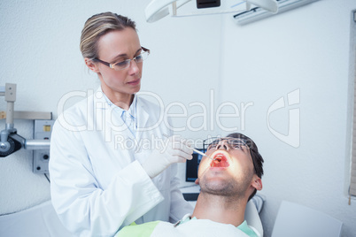 Female dentist examining mans teeth