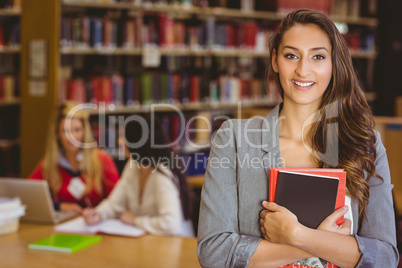 Pretty student holding books with classmates behind her