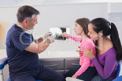 Pediatric dentist explaining to young patient and her mother the