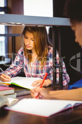 Serious student sitting at desk writing in notepad