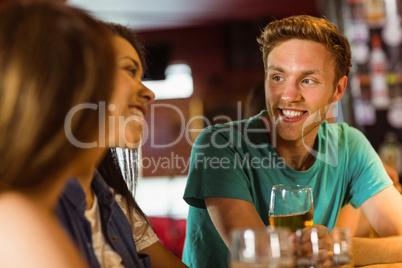 Smiling friends talking and drinking beer