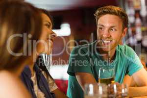 Smiling friends talking and drinking beer