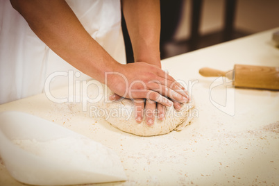 Baker kneading dough at a counter