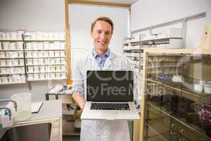 Happy pharmacist showing laptop screen