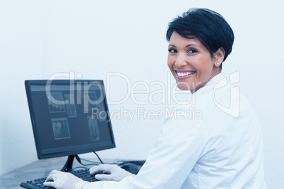 Smiling female dentist with x-ray on computer