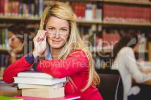 Student with reading glasses leaning on a stack of books