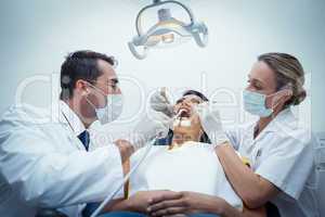 Dentist with assistant examining womans teeth