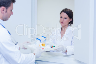 Doctor giving tray with blood sample to his colleague