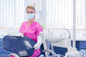 Dentist in mask looking at camera beside chair