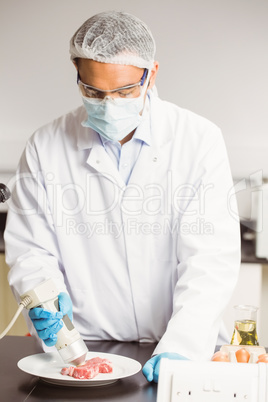 Food scientist using device on meat