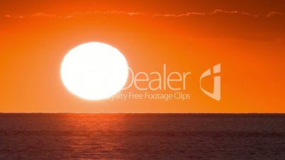 Timelapse of large, bright sun down on sunset over the sea