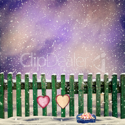 snow-covered wooden fence with two paper hearts