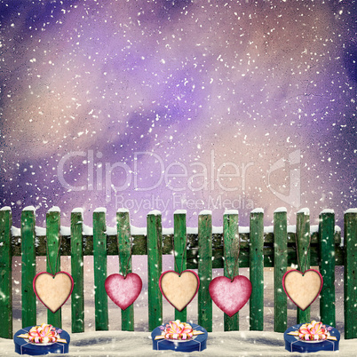 snow-covered wooden fence with hanging on it with paper hearts a