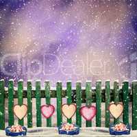 snow-covered wooden fence with hanging on it with paper hearts a
