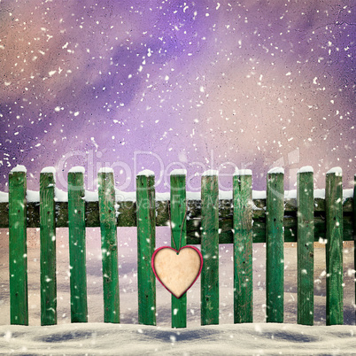 snow-covered wooden fence with  paper heart