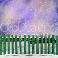 snowy old green wooden fence and falling snow