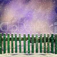 snowy old green wooden fence and falling snow