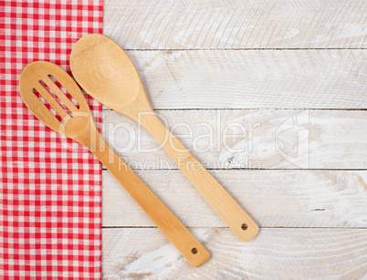 Kitchen utensils with dish towel on wooden background