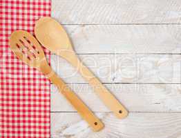 Kitchen utensils with dish towel on wooden background