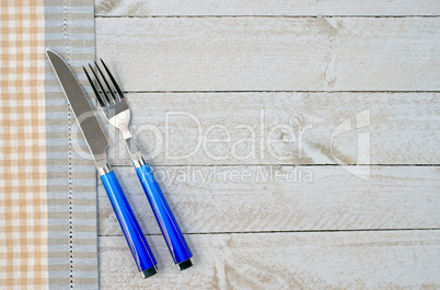 Fork and knife on wooden background with table cloth