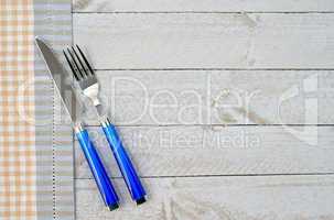 Fork and knife on wooden background with table cloth