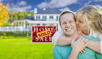 Happy Couple In Front Sold Real Estate Sign and House