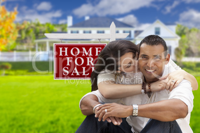Hispanic Couple, New Home and For Sale Real Estate Sign