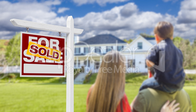 Family Facing Sold For Sale Real Estate Sign and House