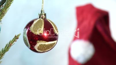Red ball on the tree on the background of Santa Claus hat