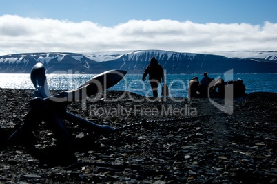 Backlit Zodiac crew come ashore beside anchor