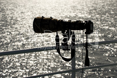 Backlit camera with long lens on railing