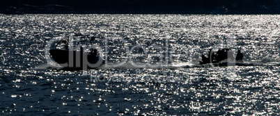 Backlit speedboat pulling inflatable banana at sea