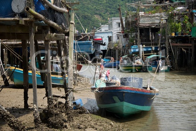 Blue boat moored beside Chinese stilted house