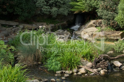 Blurred waterfall and rocky riverbed in sunshine