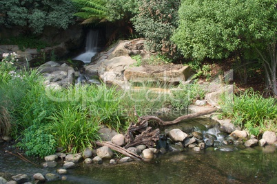 Blurred waterfall and rocky stream in sunshine