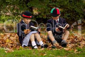 Brother and sister reading among autumn leaves