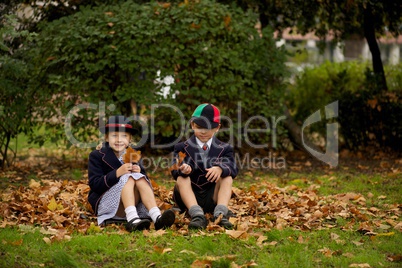 Brother and sister sitting on autumn leaves