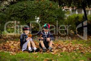 Brother and sister sitting on autumn leaves