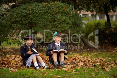 Brother and sister sitting reading among leaves