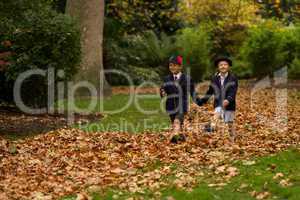 Brother and sister walking hand-in-hand through leaves