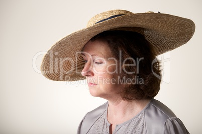 Brunette in wide-brimmed straw hat looking down