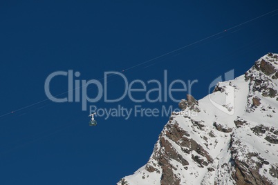 Cable car in blue sky above ridge