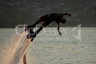 Close-up of Flyboarder diving into dusk sea