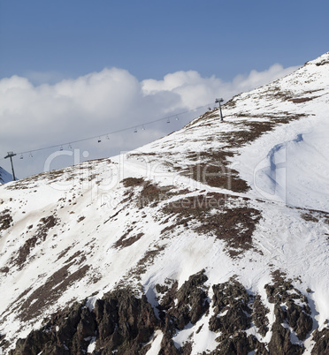 Off-piste slope with stones and chair-lift in little snow year