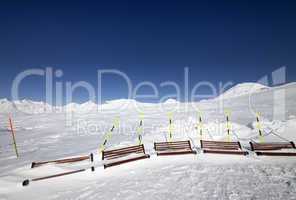 Ski slope and wooden benches in snow