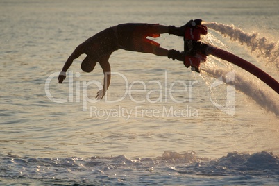 Close-up of diving Flyboarder backlit against waves