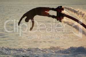 Close-up of diving Flyboarder backlit against waves