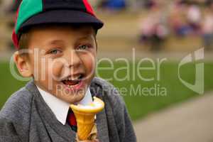 Close-up of laughing uniformed schoolboy eating ice-cream